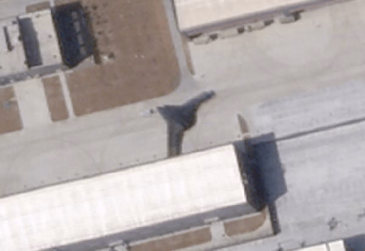 Chiếc UAV cánh bay lớn thứ hai (mũi tên xanh lá) xuất hiện trong ảnh đang đỗ bên ngoài một nhà chứa thuộc khu phức hợp an ninh cao mới xây dựng ở phía đối diện của căn cứ. Mẫu này có thiết kế dạng “cánh diều gãy” với sải cánh khoảng 137 feet, tuy nhiên có vẻ trọng lượng cất cánh lớn hơn đáng kể và trần bay thấp hơn so với mẫu cánh bay lớn hơn.