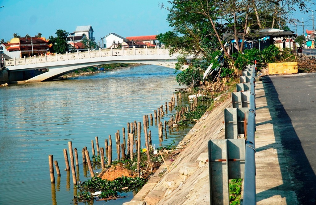 Đoạn bờ kè bê tông còn lại ven bờ nam sông Phổ Lợi đoạn gần cầu Mỹ An trong cảnh dang dở, cọc cừ nằm chỏng chơ.