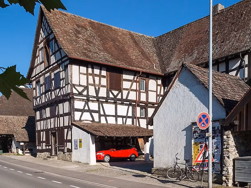 Sở dĩ Büsingen am Hochrhein có vị trí địa lý "đặc biệt" như vậy là nguồn từ mâu thuẫn gia tộc vào năm 1693. Khi ấy, thành phố này thuộc quyền kiểm soát của lãnh chúa Áo tên là Eberhard Im Thurn. Dù sinh ra trong một gia đình theo đạo Tin Lành, Eberhard bị buộc tội bí mật theo Công giáo sau một cuộc cãi vã với mục sư thị trấn. Ảnh: Junkerhaus (Bj. 1579) in… @ JoachimKohlerBremen.