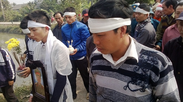 Con trai nạn nhân ôm di ảnh cha. Con trai nạn nhân ôm di ảnh cha.