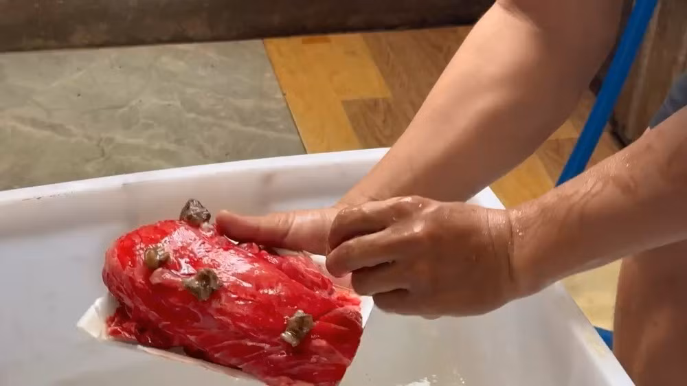 Da đà điểu được cắt thành lát rồi rải đều lên thịt lợn. Ảnh: CA