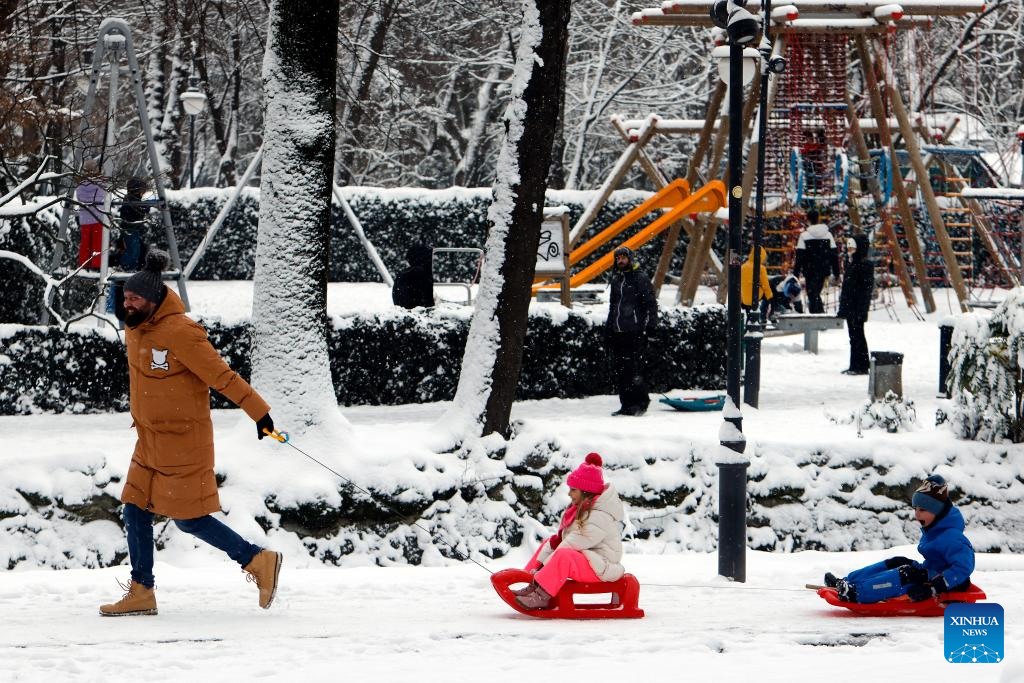 Người đàn ông kéo hai chiếc xe trượt tuyết chở các con. Được biết, nhiều khu vực ở Romania đã được đặt trong tình trạng cảnh báo màu vàng do tuyết rơi dày đặc và gió tăng cường.