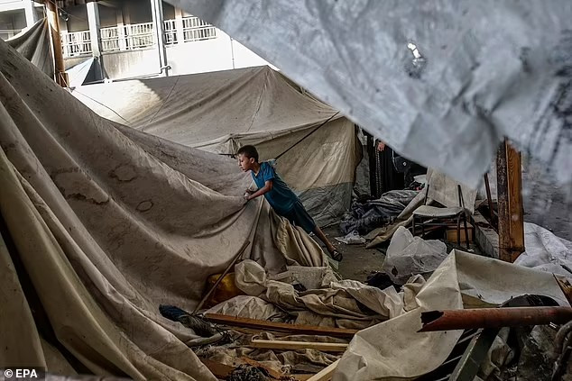 Một bé trai Palestine kiểm tra căn lều của gia đình mình bên trong trường Al Jerjawi, thành phố Gaza, bị phá hủy trong cuộc không kích của Israel. Ảnh: EPA.