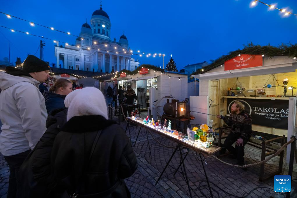 Du khách quan sát một người bán hàng tại chợ Giáng sinh Helsinki ngày 5/12.