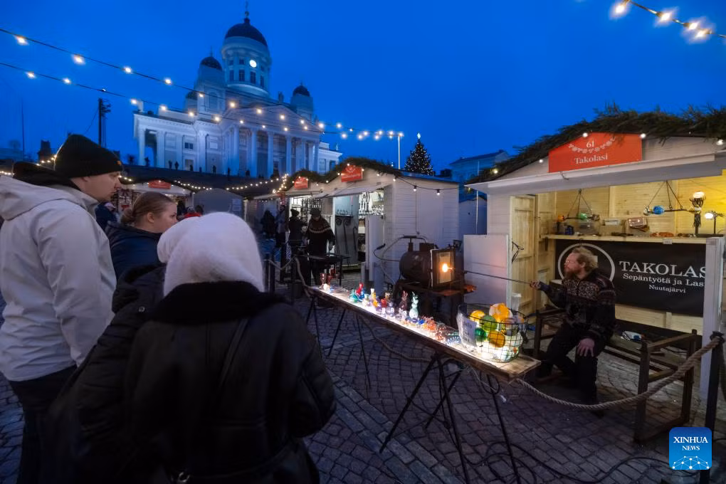 Du khách quan sát một người bán hàng tại chợ Giáng sinh Helsinki ngày 5/12.