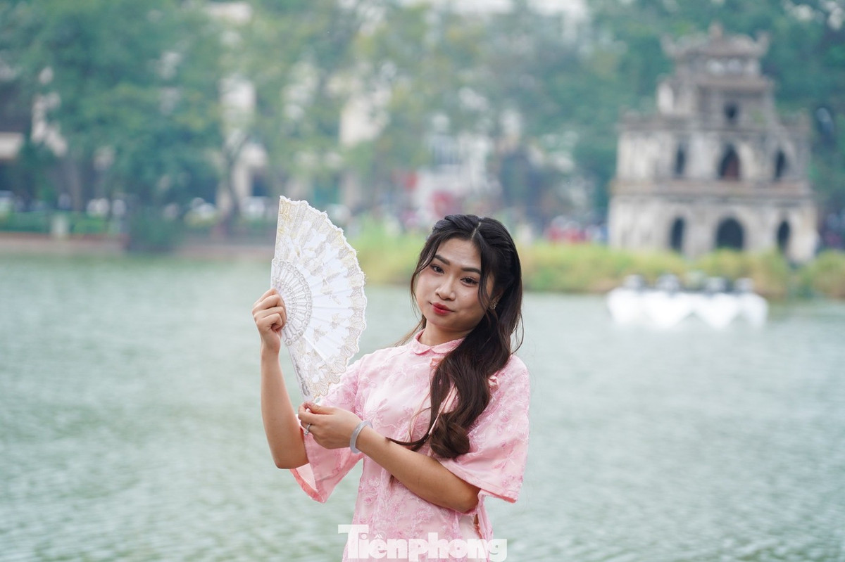 Các bạn trẻ xúng xính áo dài, rạng rỡ check-in bên bờ hồ Hoàn Kiếm trong tiết trời nắng đẹp.