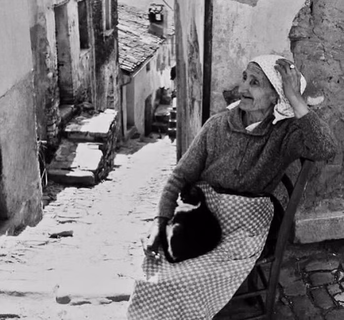 Cụ bà ngồi nghỉ ngơi trong con hẻm ở một làng quê tại Italy những năm 1960.