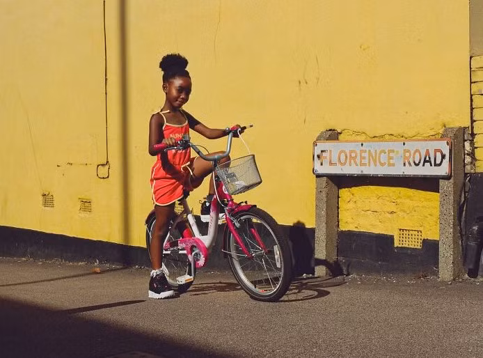 Bé gái đạp xe trong một ngày nắng ở London.