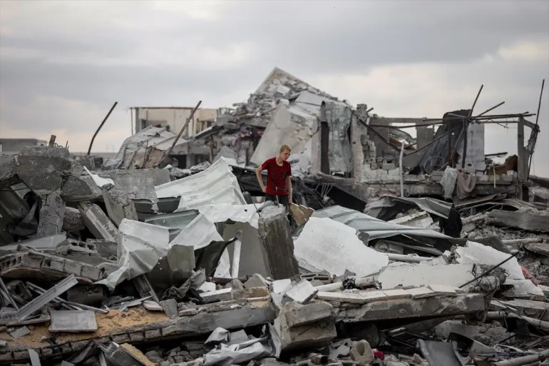 Một thanh niên đứng giữa đống đổ nát của một ngôi nhà bị phá hủy ở thành phố Gaza. Ảnh: Anadolu.