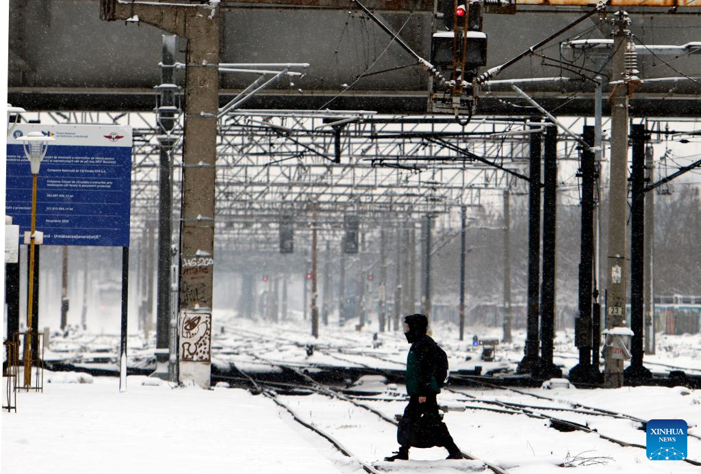 Người đàn ông đi bộ tại khu vực nhà ga phủ đầy tuyết trắng ở Romania.