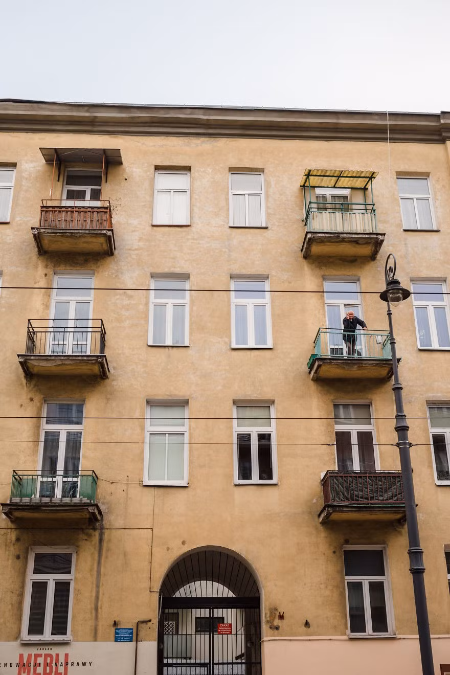 Một cư dân đứng ở ban công chào người chụp ảnh.