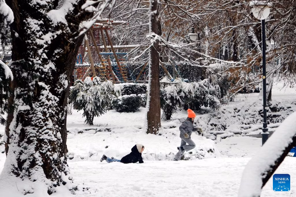 Hai em nhỏ thích thú chơi đùa giữa khung cảnh tuyết trắng.