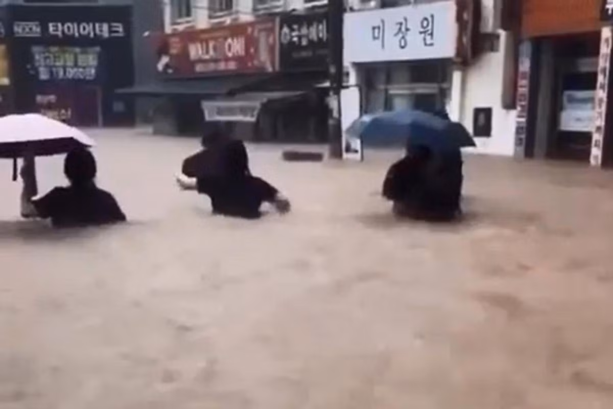 Người dân lội qua dòng nước bùn trên một con phố ở Yongbong-dong, quận Buk, Gwangju, ngày 17/7. Ảnh: Yonhap.