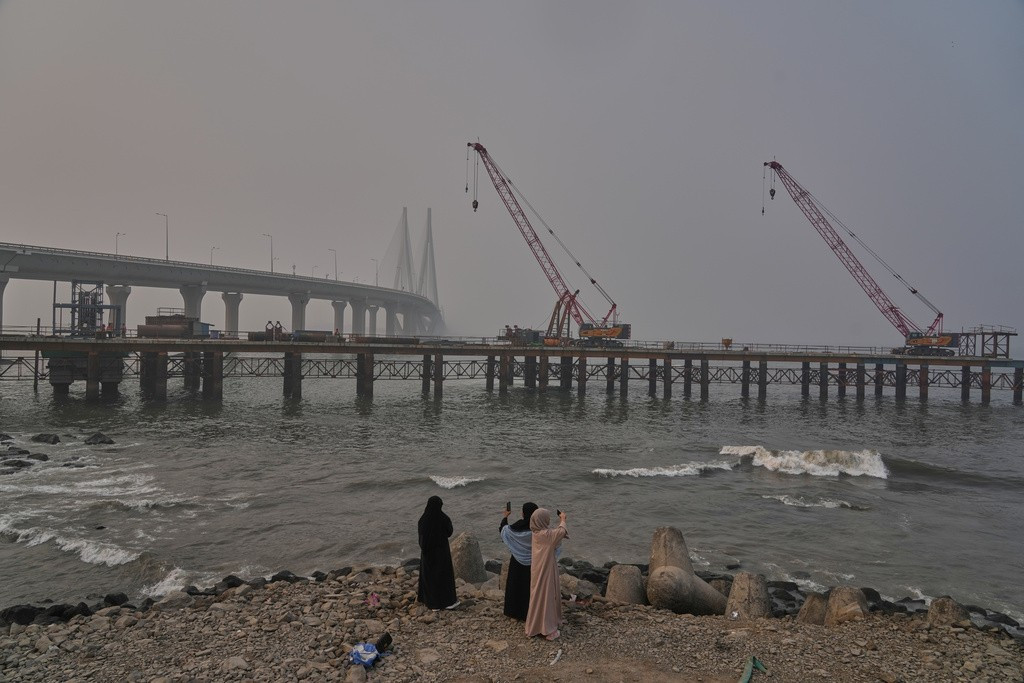 Những người phụ nữ chụp ảnh một công trình đang được xây dựng với cầu vượt biển Bandra-Worli ở phía sau, tại Mumbai ngày 1/2.
