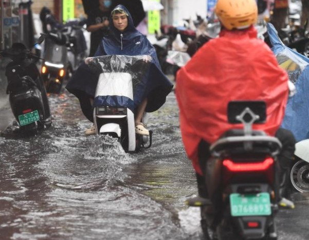 Người dân đi xe qua con đường ngập nước ở Hải Khẩu.