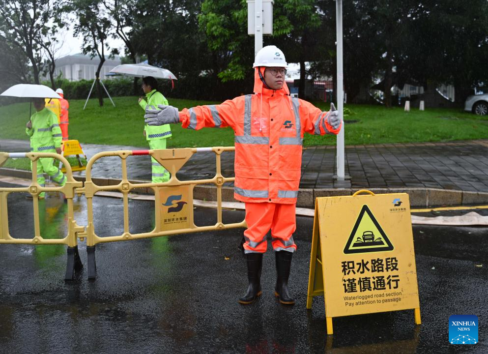 Một nhân viên điều hướng giao thông gần một con đường ngập nước ở Thâm Quyến, tỉnh Quảng Đông, ngày 20/7.