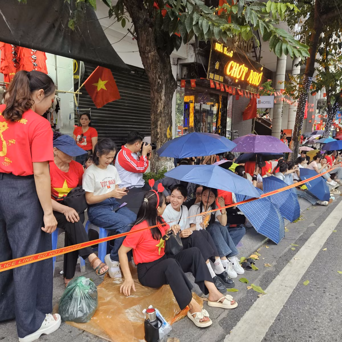 Người dân có mặt từ sớm, sử dụng ô, áo mưa, bạt để che mưa.