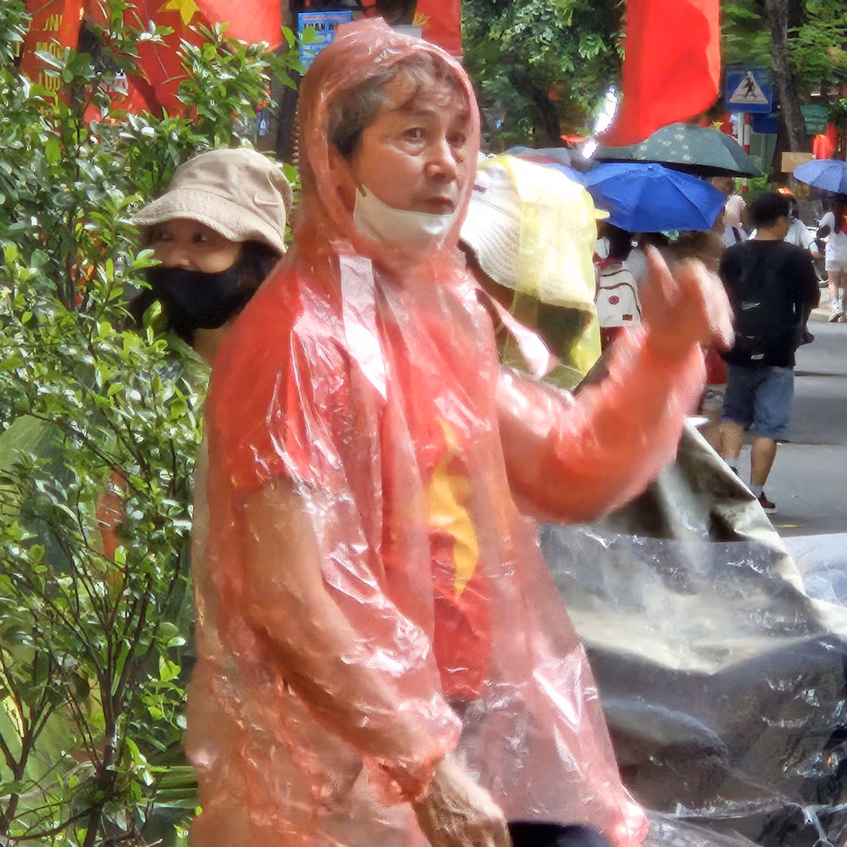 Nhiều người mặc áo mưa, che ô giữ nguyên vị trí.