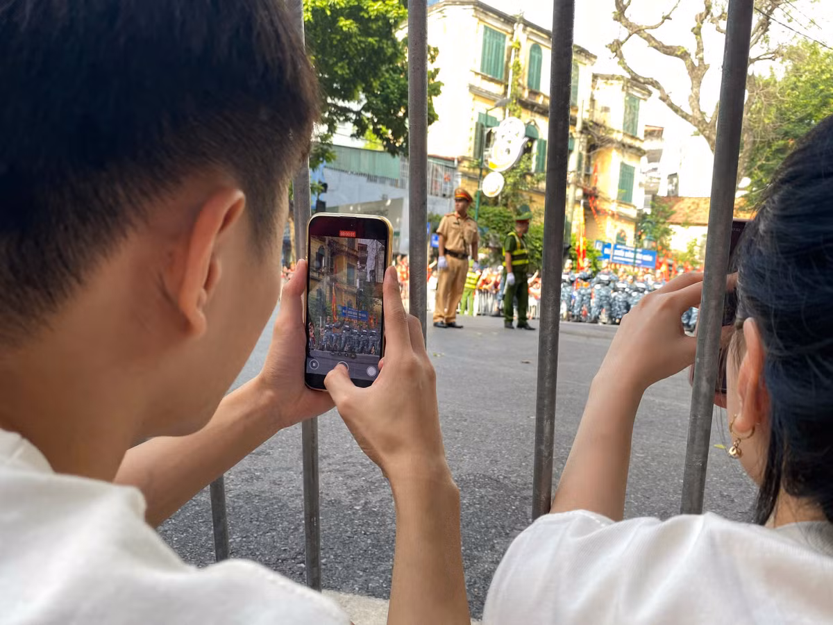 Bạn trẻ chụp ảnh khi đoàn diễu binh đi qua.