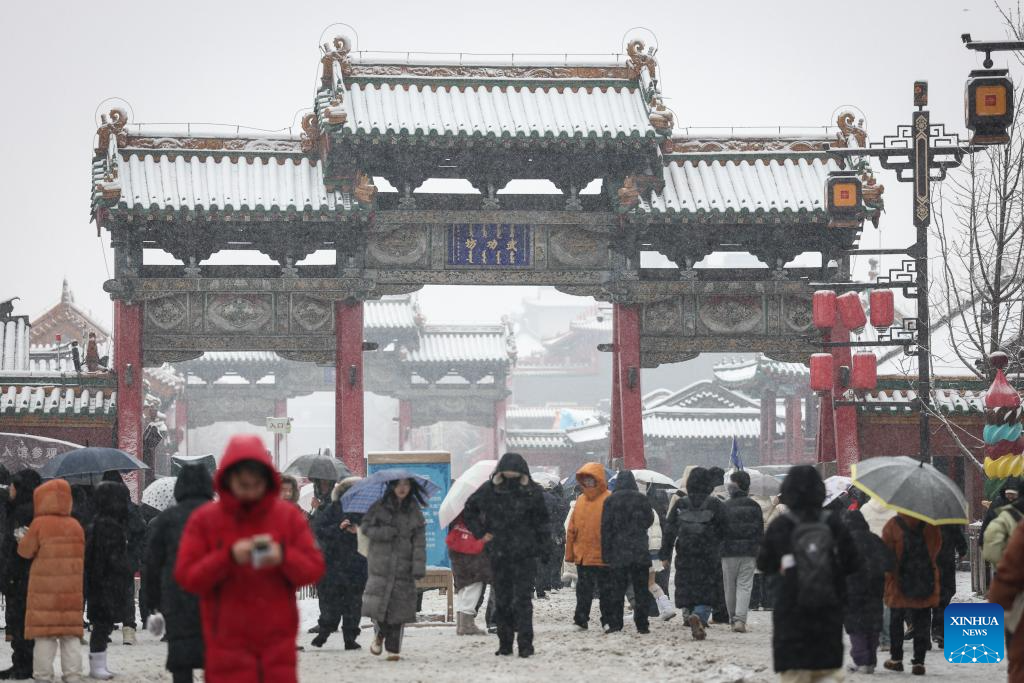 Mọi người đi bộ dưới trời mưa tuyết bên ngoài Cố cung Thẩm Dương.