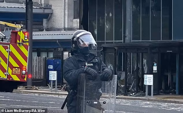 Cảnh sát đứng trước Trung tâm giải trí Larne sau khi nơi này bị đốt phá. Ảnh: PA.