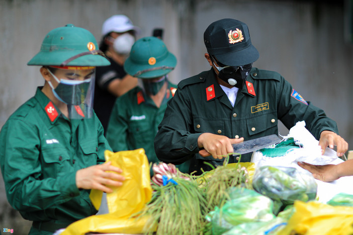 Những phần rau xanh gồm bắp cải, củ cải, cải thảo, cà chua... được các chiến sĩ phân chia vào những chiếc túi nylon lớn trước khi đưa đến từng nhà dân. (Ảnh: Zing)