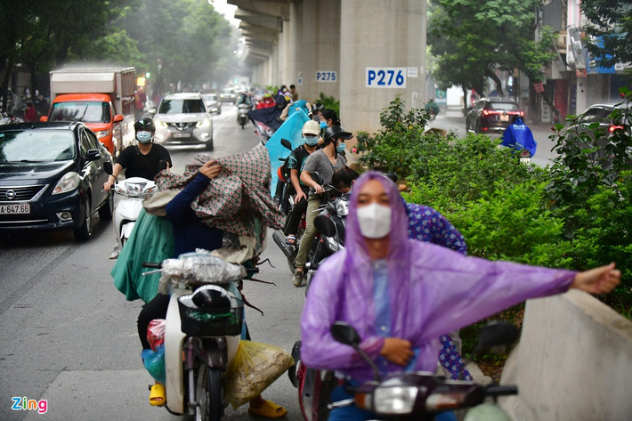 7h35 là thời điểm mưa lớn ở khu vực quận Cầu Giấy. Trên đường Xuân Thủy, nhiều người đi xe máy tạt vào trú và mặc áo mưa dưới đường tàu trên cao tuyến Nhổn - ga Hà Nội. Ảnh: Nhật Sinh.