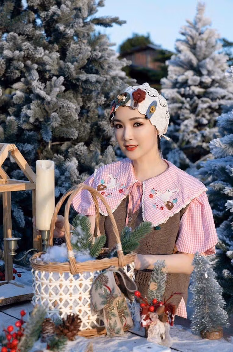 Giữa khung cảnh rừng thông phủ tuyết, bàn gỗ nhỏ bày nến, giỏ mây và những món decor Noel, Hoa hậu Đền Hùng toát lên vẻ đẹp dịu dàng, an yên như bước ra từ một câu chuyện mùa đông.