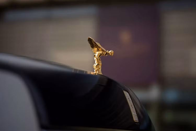 Trên nắp capo, biểu tượng Spirit of Ecstasy được chế tác từ vàng khối 18K và mạ thêm vàng 24K chống xỉn màu. Bệ đỡ tượng được đúc tay bằng men trắng, khắc dòng chữ Phantom Centenary.