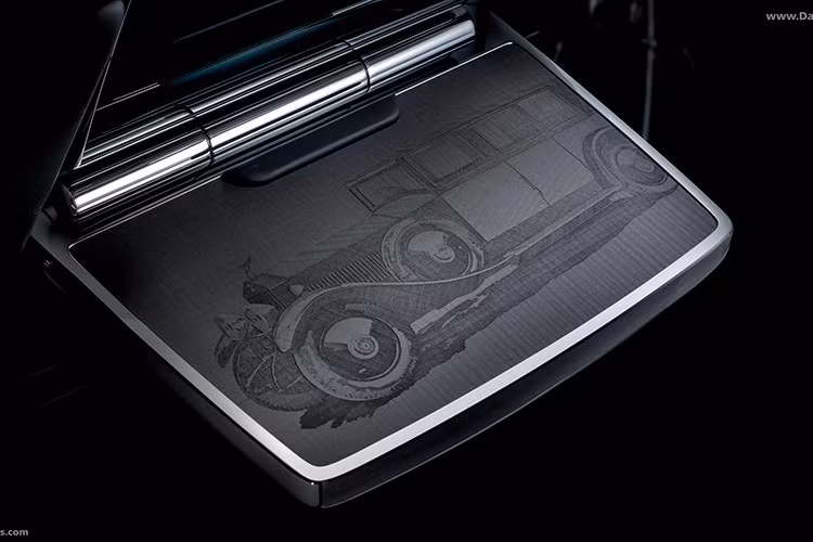 Gỗ Blackwood nhuộm màu được khắc laser và dát vàng 24K, tạo nên hiệu ứng chiều sâu độc đáo. Các bàn gập phía sau khắc hình Phantom I 1925 và Phantom VIII, như lời tri ân đến quá khứ và hiện tại. Một điểm nhấn đặc biệt khác là bầu trời Starlight Headliner được thêu tay 440.000 mũi, tái hiện những cột mốc trong lịch sử dòng xe.