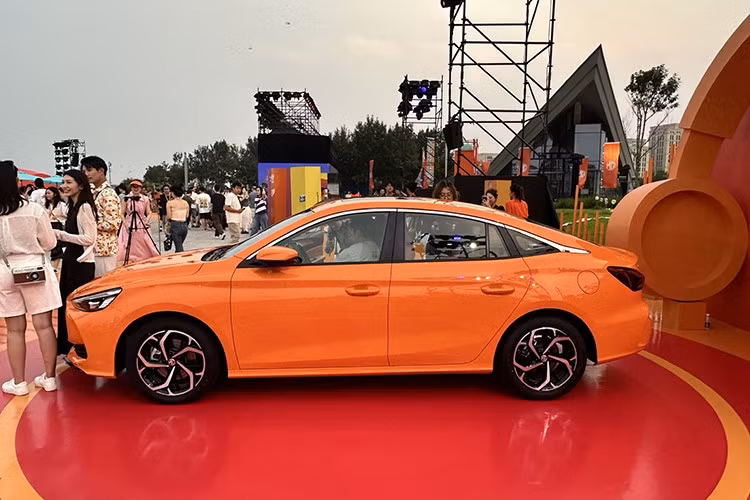 MG5 2026 vẫn giữ nguyên kiểu dáng fastback thể thao của thế hệ trước, đồng thời bổ sung hai tùy chọn màu ngoại thất mới: cam và xám, bên cạnh đỏ và trắng. Phần đầu xe nổi bật với lưới tản nhiệt dạng thác nước cỡ lớn, kết hợp cùng đèn pha mảnh và nắp ca-pô có gân nổi.