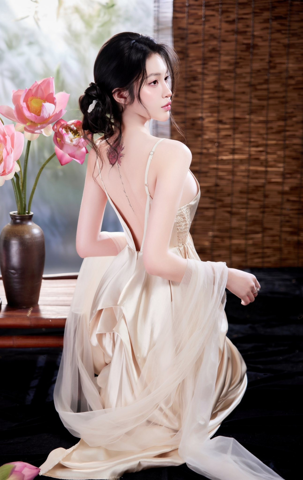 Chiếc đầm lụa màu nude/vàng champagne khoét sâu, thiết kế lưng trần táo bạo đã tạo nên sự tương phản thú vị. Nếu hoa sen tượng trưng cho sự thanh cao, thì chiếc đầm lại tôn lên trọn vẹn đường cong và vẻ quyến rũ hiện đại của Triều Tiên.