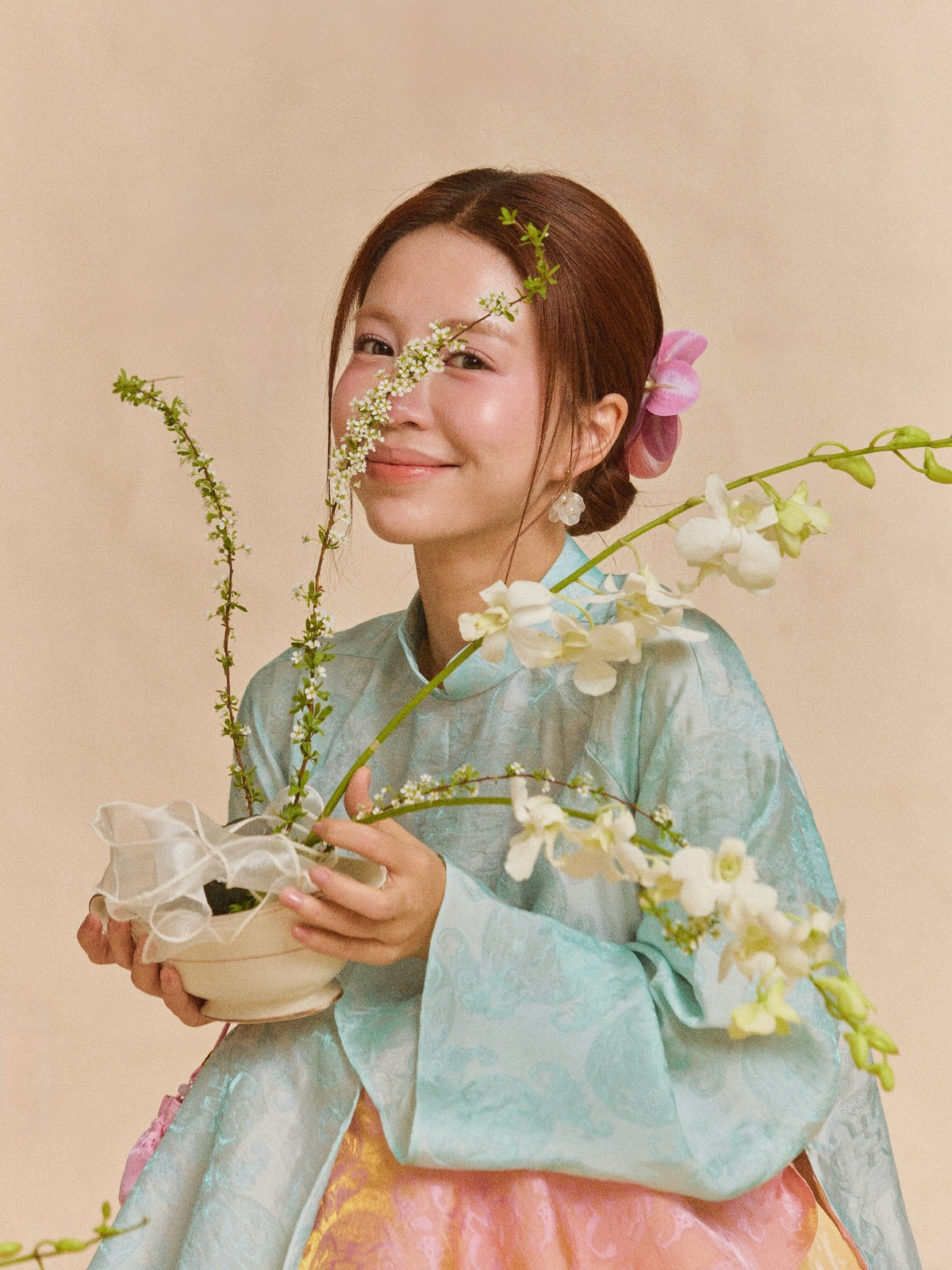 Điểm đặc biệt trong loạt ảnh là cách Mẫn Tiên kết hợp áo dài với những phụ kiện mang đậm tính biểu tượng ngày Tết như hoa tươi, giỏ tre hay những chi tiết trang trí truyền thống.