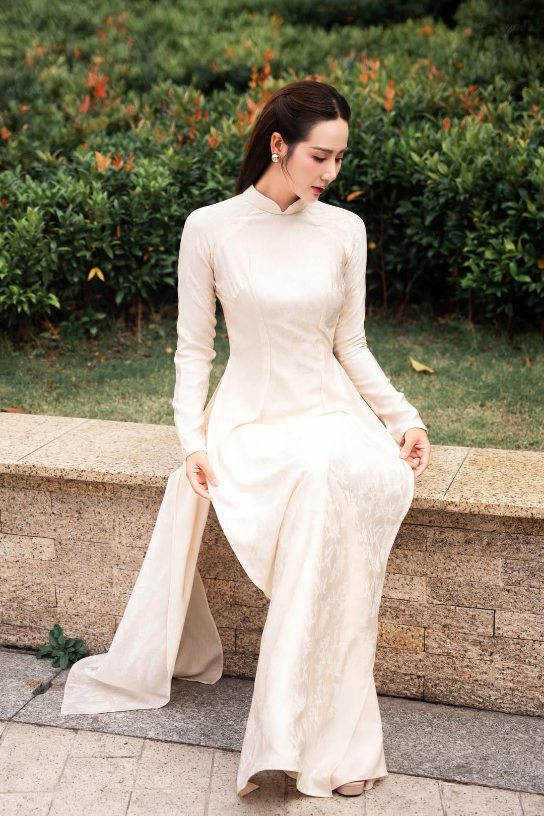 Chất liệu vải trơn pha họa tiết chìm giúp tổng thể trang phục trở nên sang trọng nhưng vẫn giữ được nét truyền thống. Gam màu trắng ngà làm nổi bật làn da sáng mịn và khí chất thanh lịch vốn là “đặc sản” của nữ diễn viên.