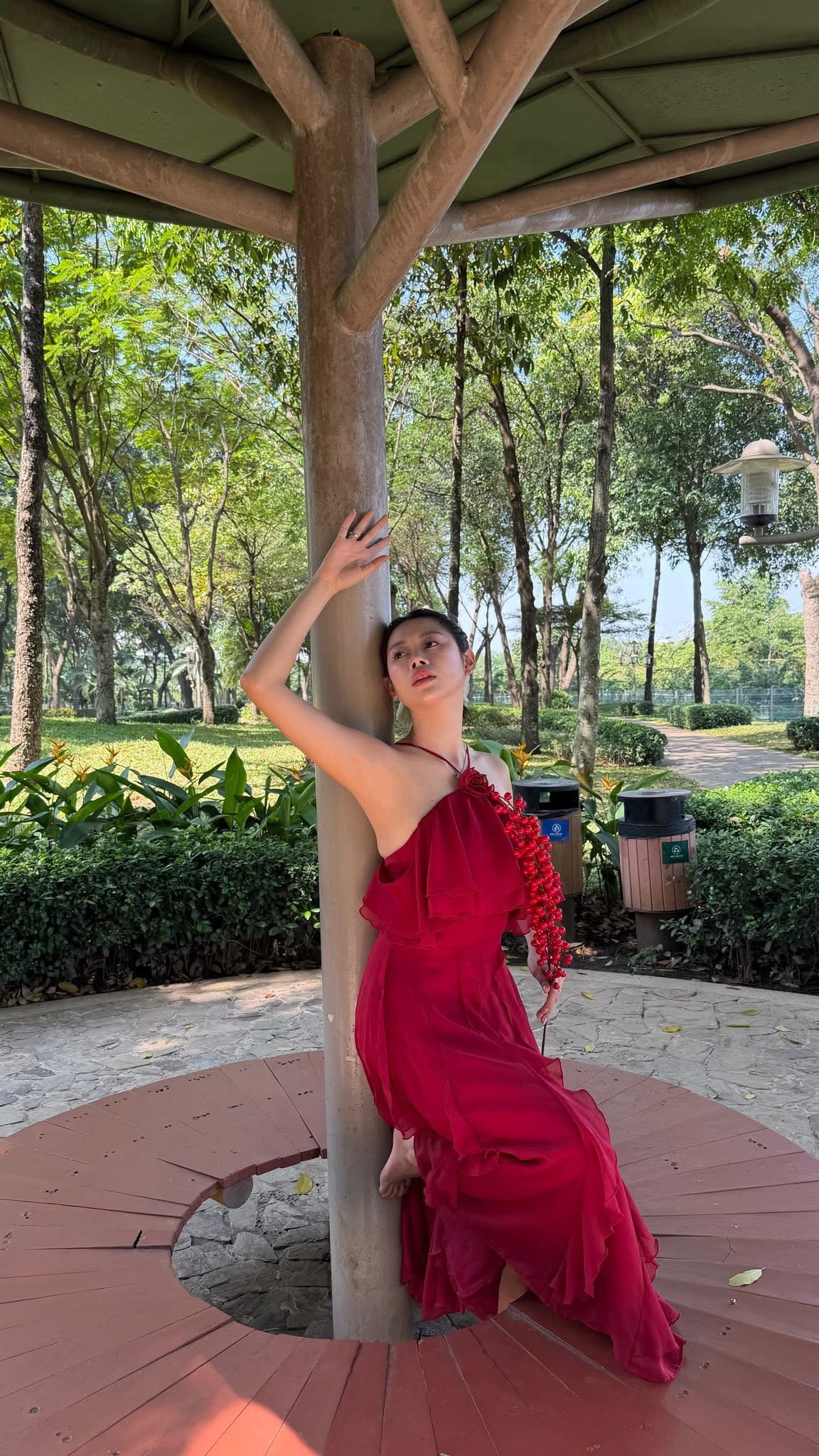 Trong loạt ảnh mới, Việt Phương Thoa diện váy đỏ nổi bật – gam màu đặc trưng của ngày Tết – nhưng thay vì tạo dáng nhẹ nhàng, dịu dàng, cô nàng lại “chơi lớn” với những tư thế chẳng giống ai: đu xà giữa công viên, nằm dài trên lối đi, ôm cây tạo dáng, hay vô tư tập máy thể dục ngoài trời.