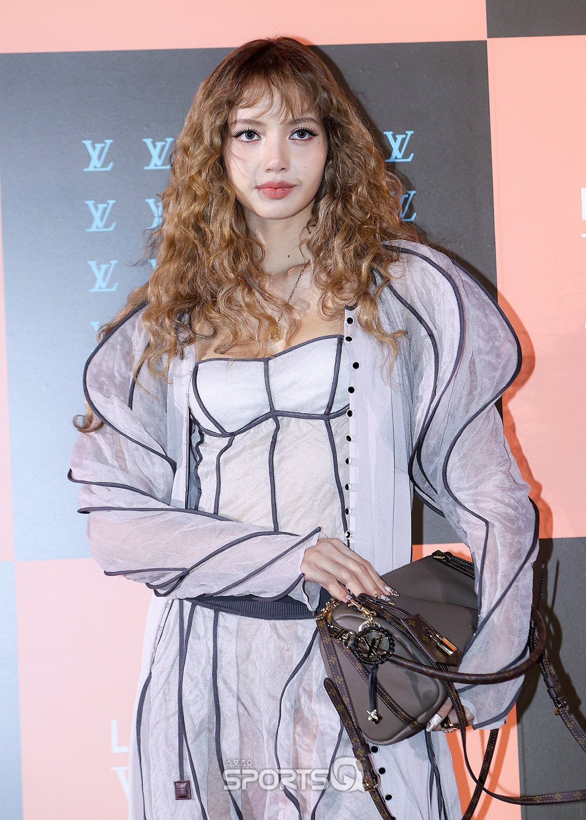 Trong ảnh, Lisa xuất hiện với mái tóc xoăn tơi bồng, tạo cảm giác phóng khoáng và đầy cá tính. Kiểu tóc xoăn nhỏ, tạo thành những lọn sóng dày, giúp tăng độ nổi bật và mang đúng tinh thần thời trang thập niên 70 nhưng được làm mới theo hướng hiện đại.