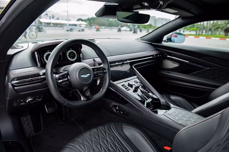 Khoang cabin của DB12 mang phong cách thể thao sang trọng, với phối màu đen - đỏ, ghế ngồi thể thao có chức năng làm mát, vô-lăng sưởi, và nhiều chi tiết ốp carbon nhám tăng thẩm mỹ.