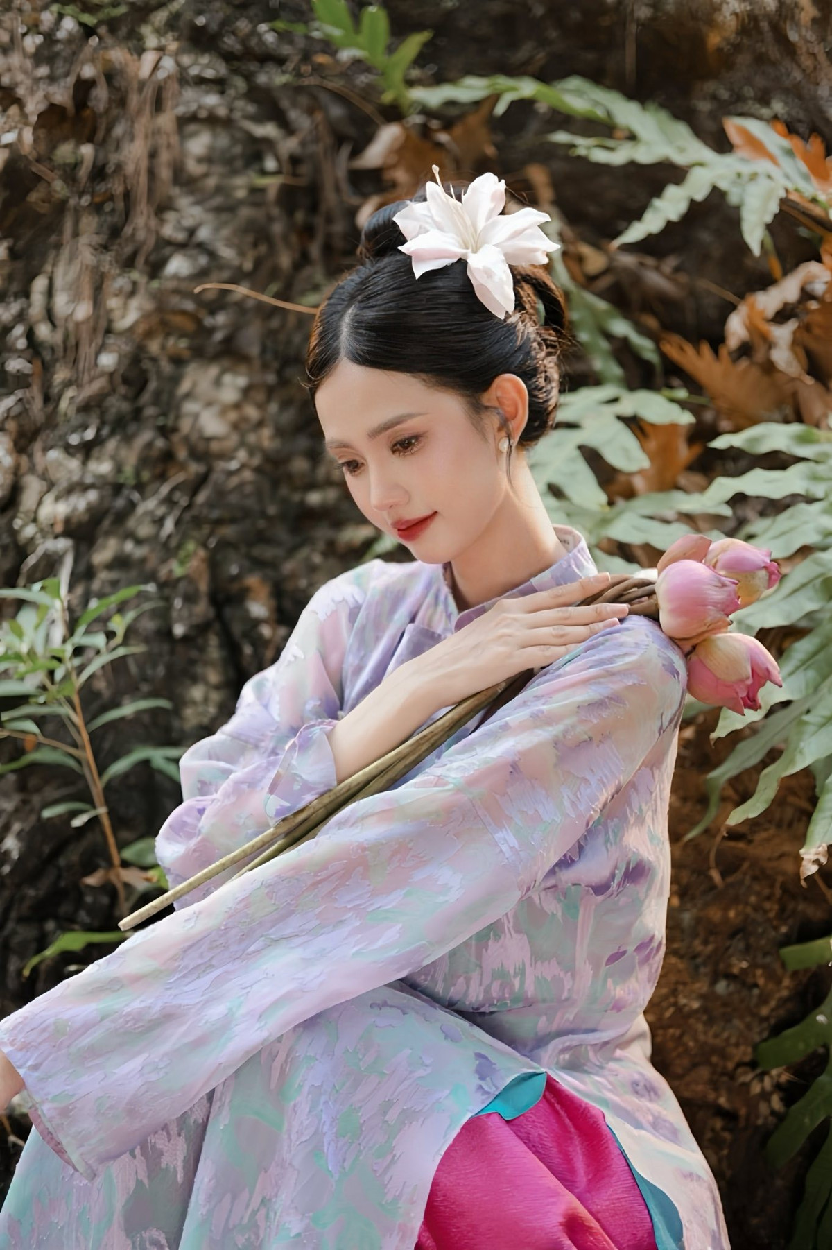 Trong bộ ảnh, Gabriella Bùi diện thiết kế áo dài mang tông tím pastel pha sắc hồng nhẹ, tạo cảm giác mềm mại và lãng mạn. Chất liệu vải mỏng, bay nhẹ theo từng chuyển động giúp tà áo thêm phần thướt tha, uyển chuyển giữa khung cảnh thiên nhiên rợp bóng cây xanh.