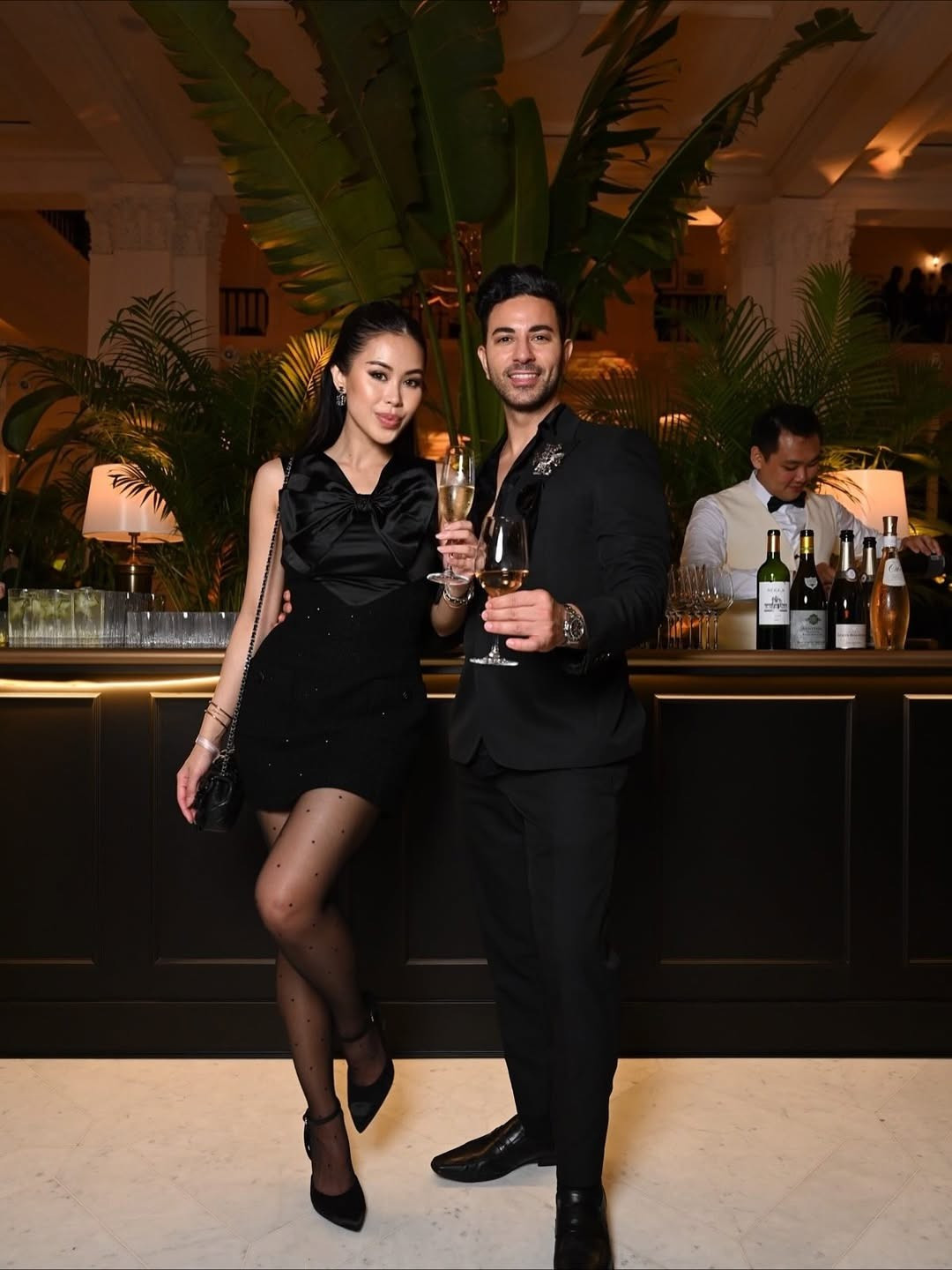 Trong ảnh Tiên Nguyễn diện đầm đen với điểm nhấn là chiếc nơ trước ngực phối cùng túi Chanel thì bạn trai gốc Dubai bảnh bao trong bộ suit lịch lãm.