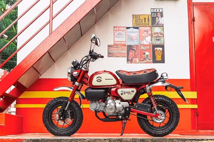 Về ngoại hình, Honda Monkey Cherry Edition nổi bật với thân xe màu đỏ, viền kem và họa tiết quả anh đào, tạo nên sự kết hợp hài hòa giữa nét vui tươi hiện đại và phong cách cổ điển của những năm 80.