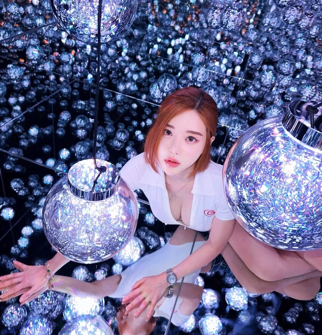 Dưới ánh đèn phản chiếu từ hàng trăm quả cầu thủy tinh, gương mặt gái xinh làng DJ này trông càng sắc nét với đôi mắt to tròn, ánh nhìn có chút ngây thơ nhưng lại cực kỳ cuốn hút và làn da sáng, hiệu ứng ánh sáng khiến gương mặt như phát sáng giữa căn phòng gương.