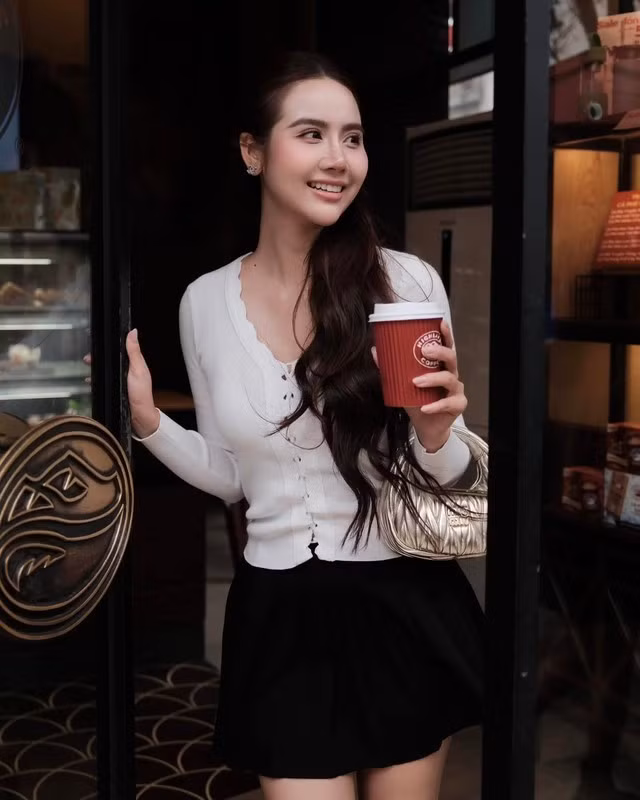 Nếu như áo len mỏng màu trắng có sự dịu dàng, trang nhã thì chân váy ngắn dáng chữ A lại rất trẻ trung, ngọt ngào. Chiếc túi xách ánh bạc ăn nhập hoàn hảo với outfit, giúp tăng vẻ long lanh cho tổng thể trang phục.