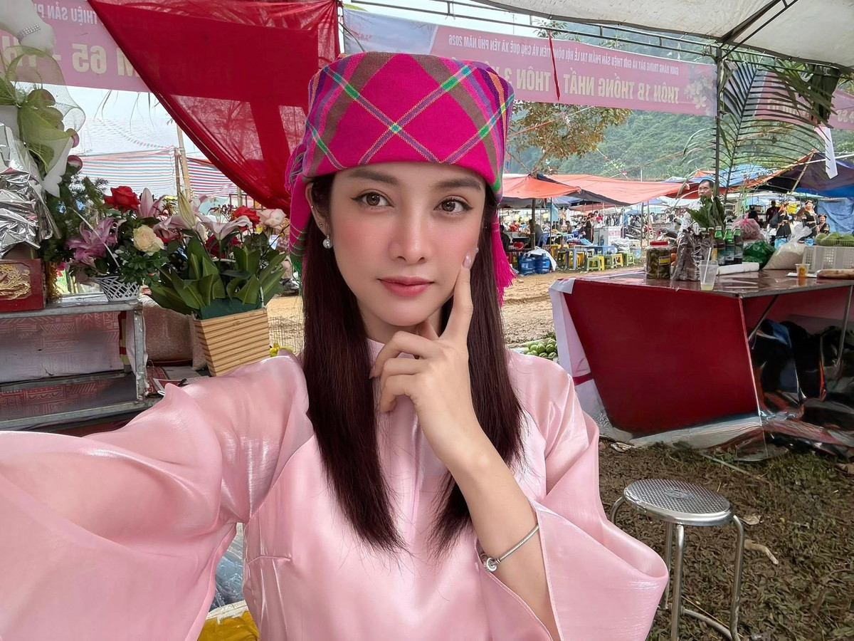 Trong loạt ảnh được chia sẻ, Trình Mỹ Duyên xuất hiện tại một lễ hội truyền thống với trang phục mang sắc hồng dịu, kiểu dáng kín đáo, thanh lịch. Điểm nhấn nằm ở chiếc khăn đội đầu rực rỡ sắc màu, giúp tổng thể vừa giữ được nét nữ tính, vừa hài hòa với không gian văn hóa bản địa. Giữa khung cảnh núi non, cờ hội và những dãy hàng quán tấp nập, hình ảnh của cô trở nên nổi bật nhưng không hề lạc lõng.