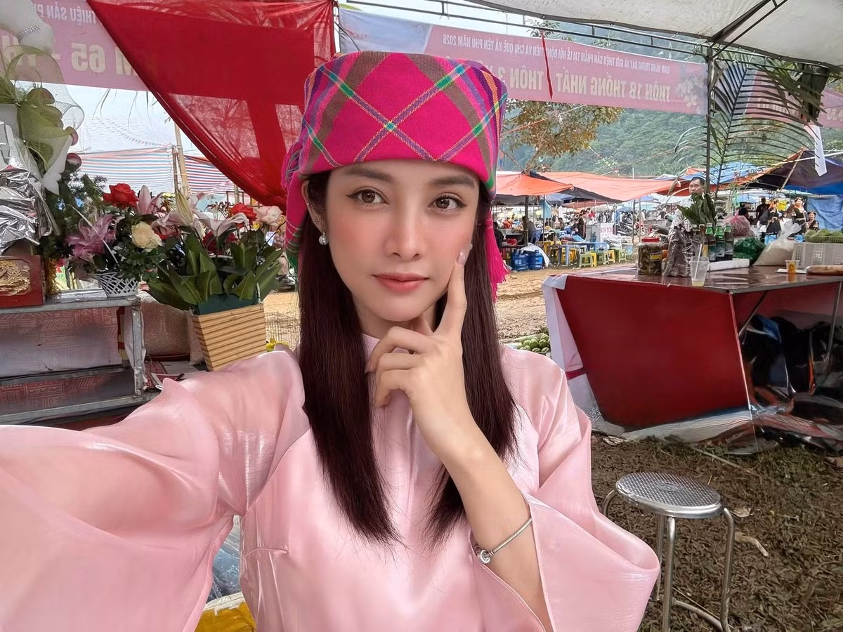 Trong loạt ảnh được chia sẻ, Trình Mỹ Duyên xuất hiện tại một lễ hội truyền thống với trang phục mang sắc hồng dịu, kiểu dáng kín đáo, thanh lịch. Điểm nhấn nằm ở chiếc khăn đội đầu rực rỡ sắc màu, giúp tổng thể vừa giữ được nét nữ tính, vừa hài hòa với không gian văn hóa bản địa. Giữa khung cảnh núi non, cờ hội và những dãy hàng quán tấp nập, hình ảnh của cô trở nên nổi bật nhưng không hề lạc lõng.