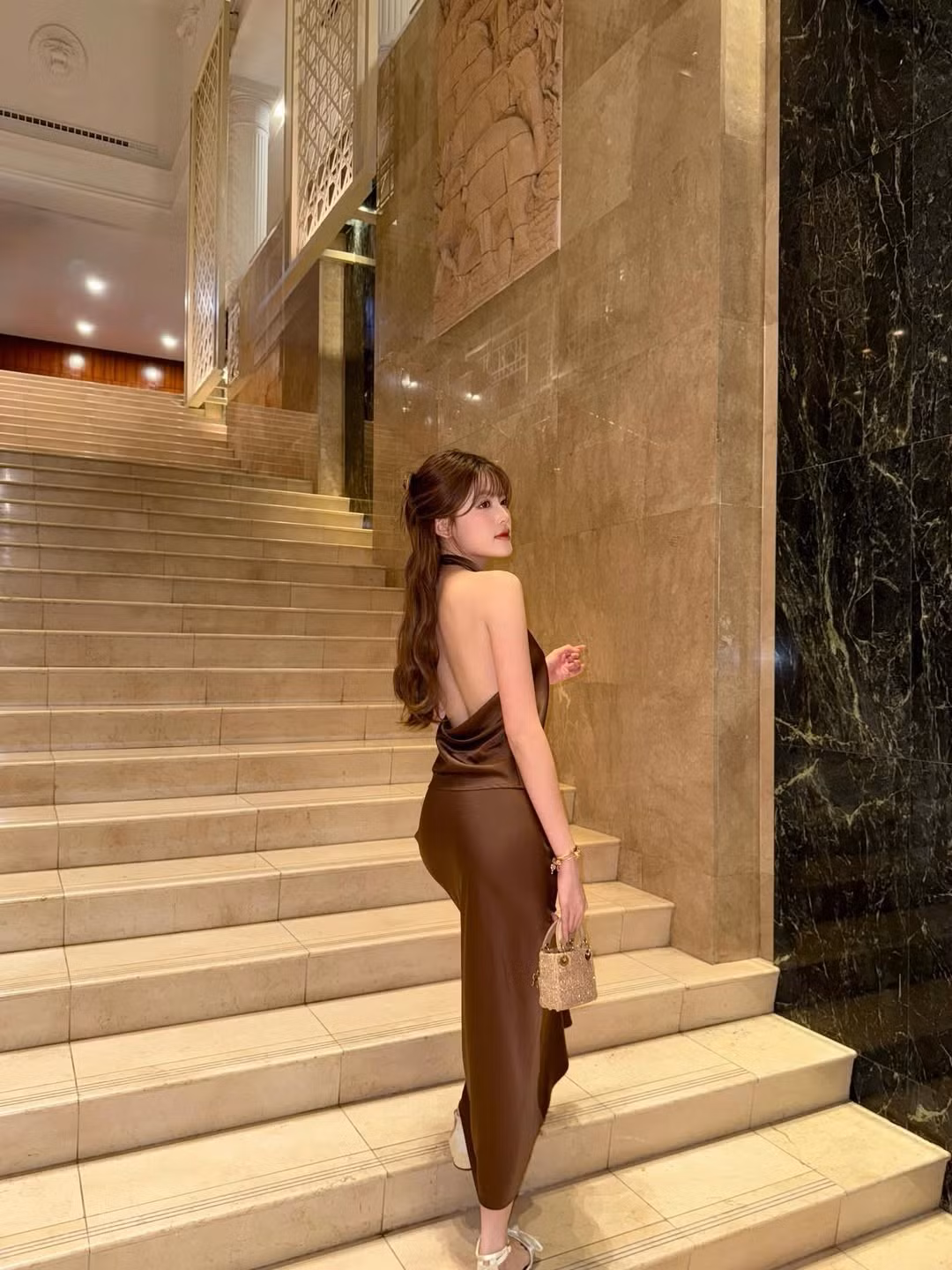 Trong loạt ảnh được chụp tại một không gian sang trọng, Tăng Mỹ Hàn xuất hiện với chiếc đầm lụa màu nâu chocolate ôm dáng đầy tinh tế. Thiết kế cổ yếm kết hợp phần lưng khoét sâu giúp cô nàng khoe trọn bờ lưng mịn màng, đường cong uyển chuyển và thần thái kiêu kỳ.