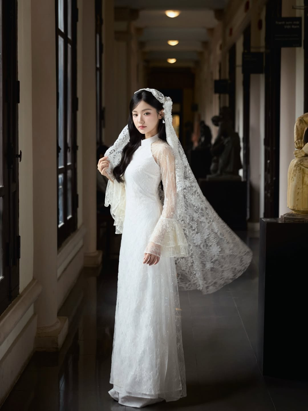 Lối trang điểm được tiết chế tối đa với tông hồng nude, lớp nền mỏng nhẹ và đôi mắt được nhấn bằng hàng mi cong tự nhiên. Kiểu tóc buông dài kết hợp cùng bông hoa trắng cài lệch phía sau tai càng làm nổi bật vẻ dịu dàng, trong trẻo. Tổng thể tạo nên hình ảnh một “nàng thơ thế hệ mới” – trẻ trung nhưng vẫn đậm chất Á Đông.