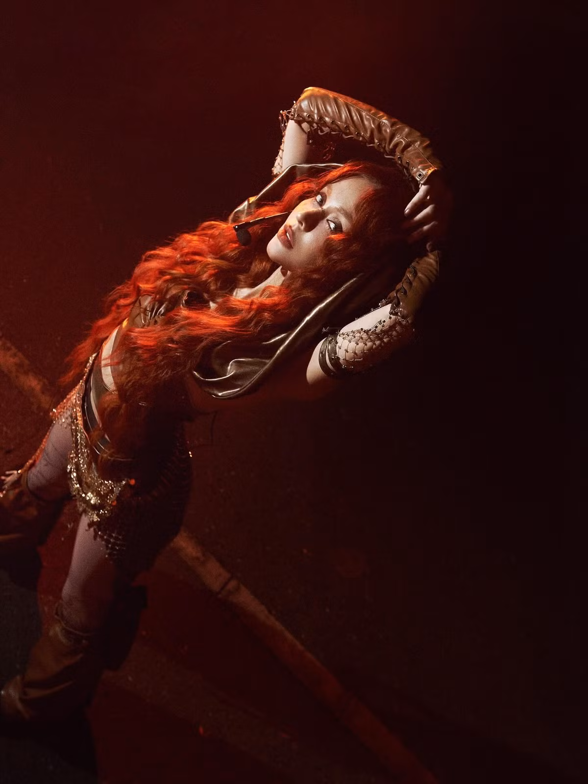 Trong concept khác, khi hóa thân với mái tóc xoăn đỏ cùng trang phục mang hơi hướng chiến binh, MLee mang đến vibe mạnh mẽ, bí ẩn. ánh sáng đỏ chiếu lên mái tóc và gương mặt khiến cô trông như bước ra từ một tác phẩm điện ảnh hành động.