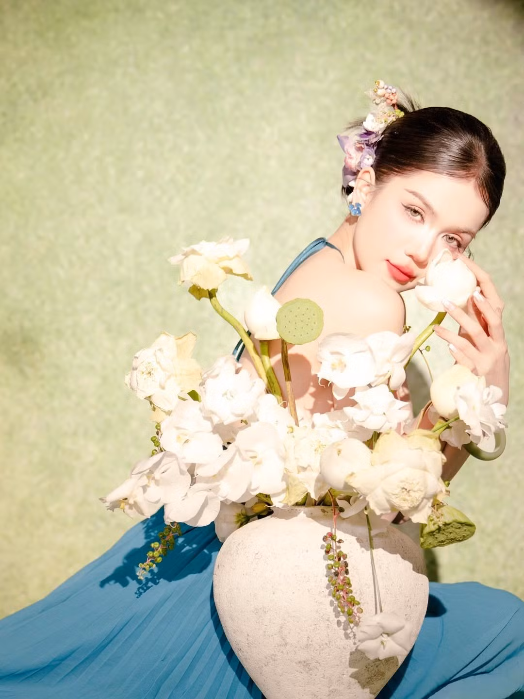 Không cần quá phô trương, chỉ với một chiếc váy yếm đơn giản và bối cảnh hồ sen, Ngọc Trinh vẫn đủ sức "đốn tim" người hâm mộ bằng vẻ đẹp tự nhiên và thần thái lôi cuốn.