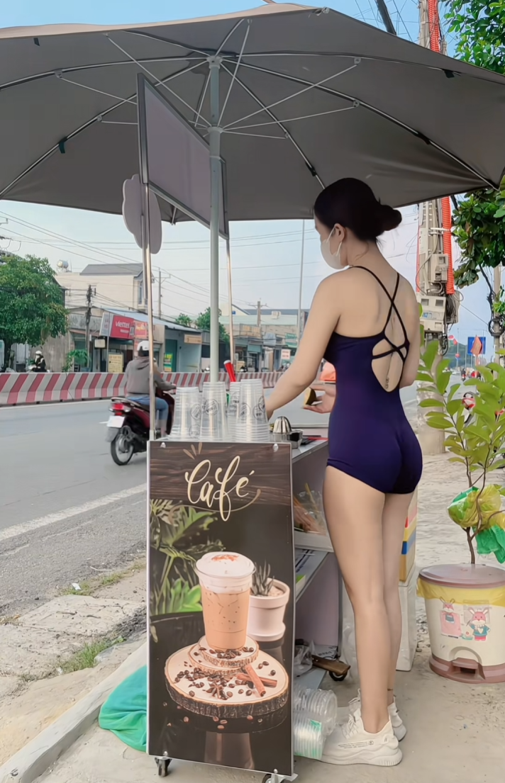 Theo đó, cô gái đứng bán cà phê nhưng trang phục sử dụng lại là một dạng trang phục trong phòng tập gym, bó sát và có những cắt xẻ táo bạo giúp tôn lên vóc dáng chuẩn chỉnh của hot girl.