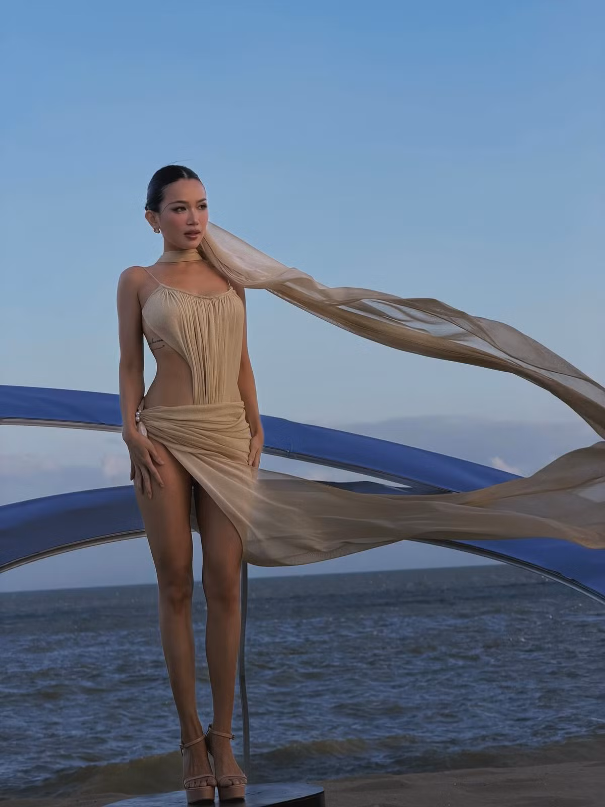 Không chỉ gây ấn tượng ở hình thể, thần thái của Sĩ Thanh cũng là yếu tố khiến bộ ảnh trở nên hút mắt. Khi thì cô thả dáng tự nhiên cùng mái tóc dài bay trong gió biển, lúc lại khẽ nhắm mắt tận hưởng nắng gió, tạo nên những khoảnh khắc vừa gợi cảm vừa đầy chất thơ. Ánh nhìn sắc sảo xen lẫn vẻ mềm mại nữ tính giúp mỗi khung hình đều mang cảm giác thời trang chuyên nghiệp như một bộ ảnh tạp chí.